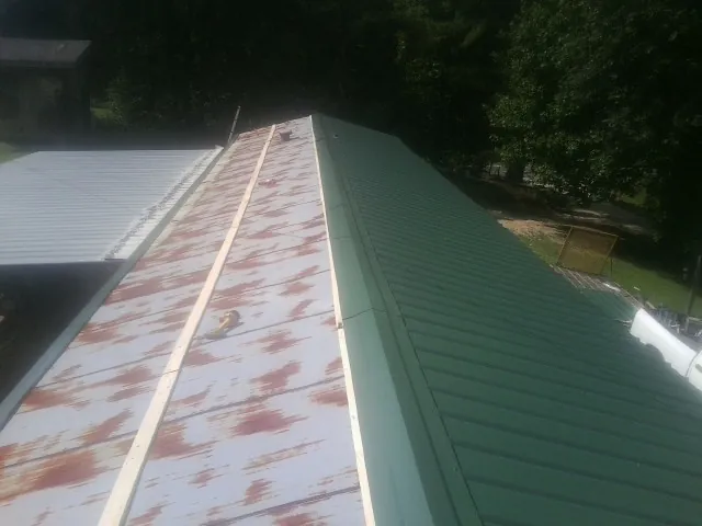 Old rusted panels beside newly installed green metal roofing — Wind Damage Roof Repair by Roofing Brothers in Cedaredge