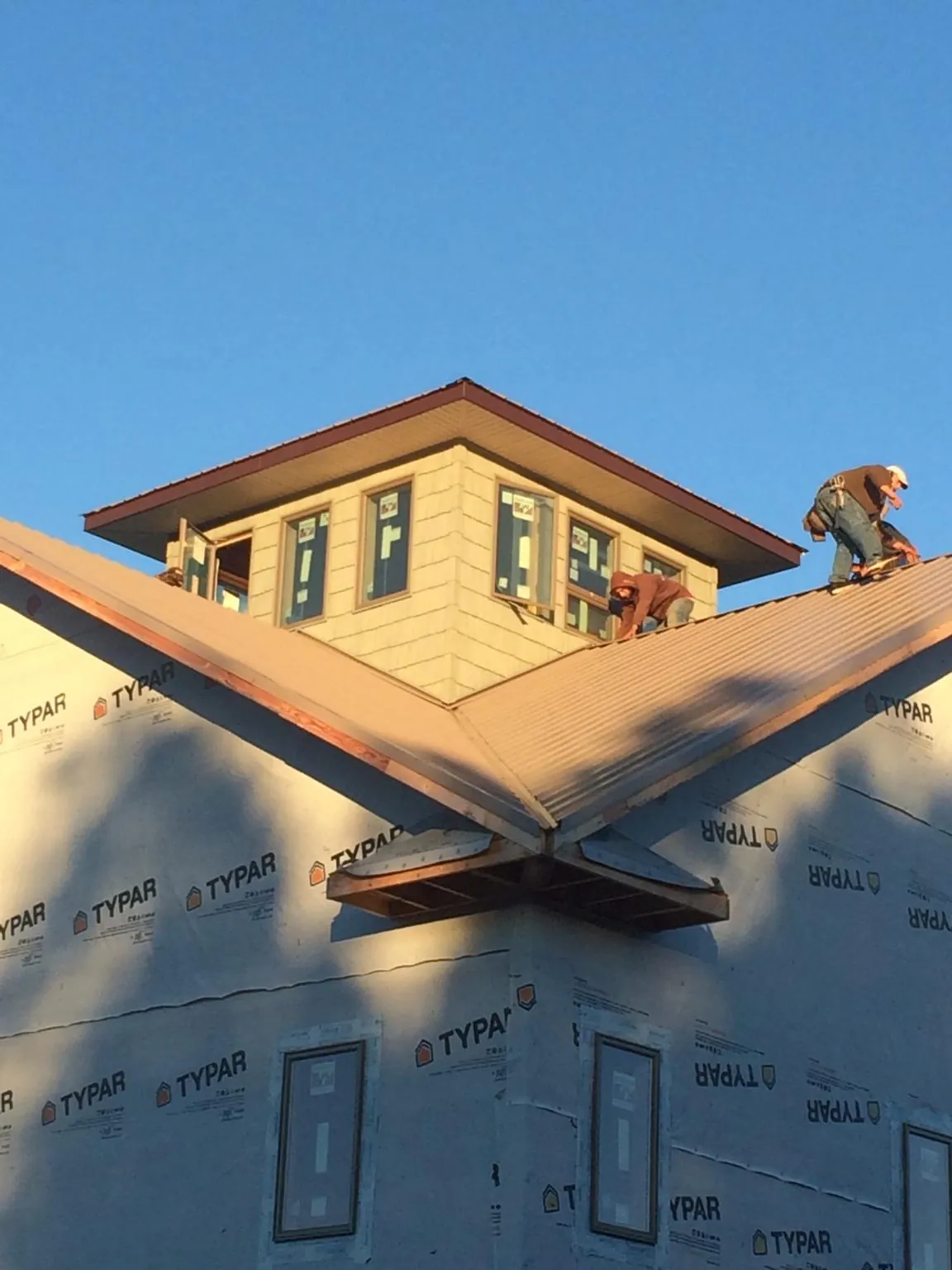Roofers working around a rooftop cupola on a new metal roof at sunset — Roof Waterproofing in Cedaredge by Roofing Brothers
